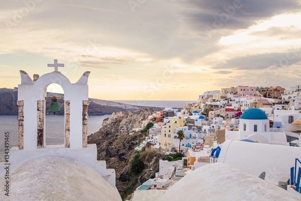 Fototapeta Scenic view of Oia, Santorini, Greece, featuring the iconic three domes viewpoint, colorful houses, and the Aegean Sea. Horizontal shot with a cloudy sky, perfect for honeymoon or wedding destination