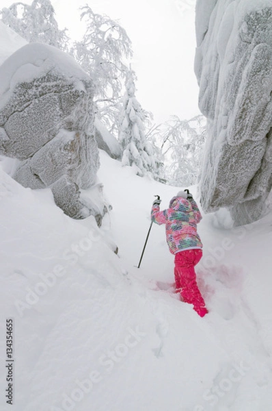 Obraz Маленькая девочка совершает зимой восхождение на гору.