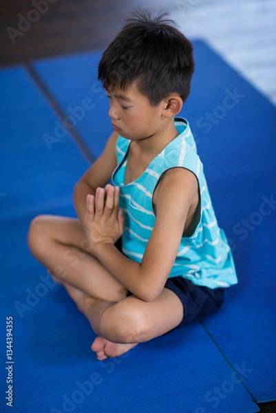 Obraz Young boy meditating on yoga mat at home, practicing mindfulness and relaxation