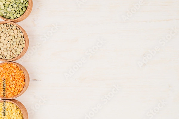 Obraz Assortment of lentils in a wooden bowls with copy space on white wood background. Top view, closeup. Healthy protein food.