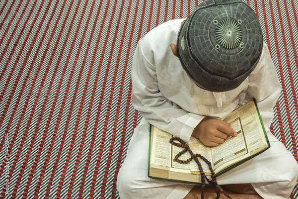 Fototapeta Boy reading al Quran during fasting month (Ramadhan ). DOF and copy space.