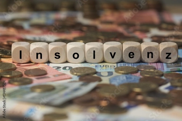 Obraz insolvenz - Holzwürfel mit Buchstaben im Hintergrund mit Geld, Geldscheine