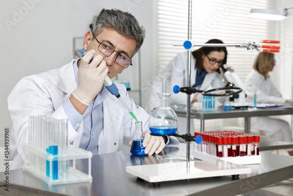 Fototapeta Scientist with micropipette and flask working in laboratory