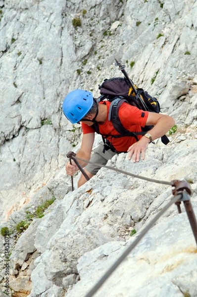 Fototapeta Mountaineer climbing up the steepy mountain in summer.