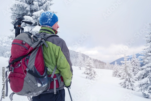 Obraz Man with backpack in snow covered forest