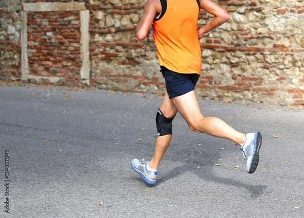 Fototapeta runner running fast with a knee brace to support muscle ligament