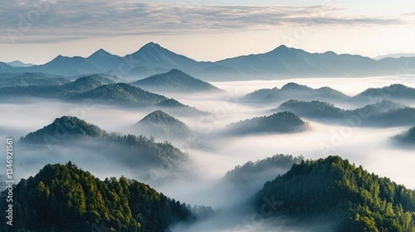 Fototapeta Majestic Peaks Emerging: An ethereal vista unfolds as rolling hills, cloaked in a veil of mist, give way to the soaring peaks in the background, creating a stunning panoramic view. 