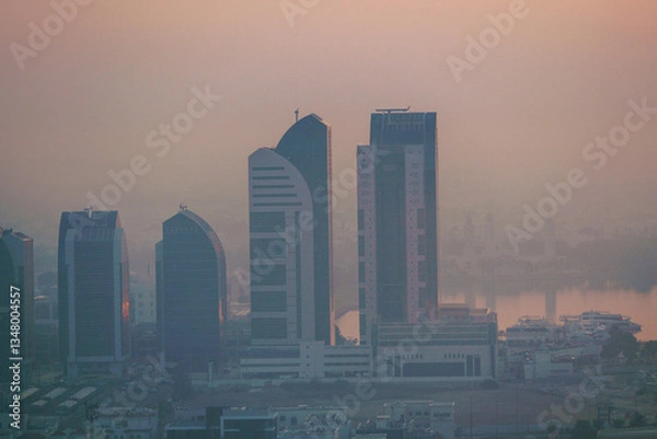 Fototapeta Aerial view of Abu Dhabi in the morning light, as the rising sun casts a golden glow over the city's modern skyline.