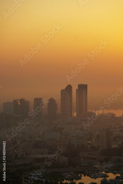 Fototapeta Aerial view of Abu Dhabi in the morning light, as the rising sun casts a golden glow over the city's modern skyline.