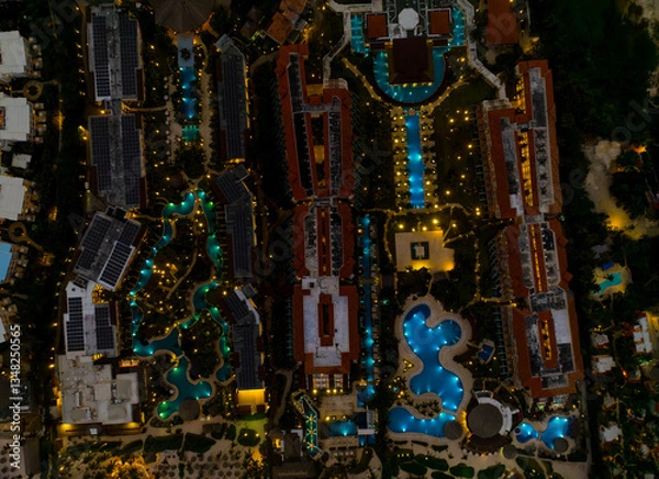 Obraz A nighttime aerial view of a resort with a pool and a hotel