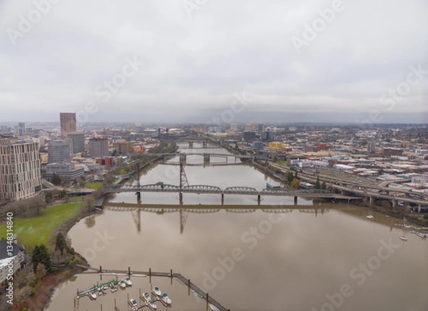 Fototapeta A city with a river running through it and a bridge over it