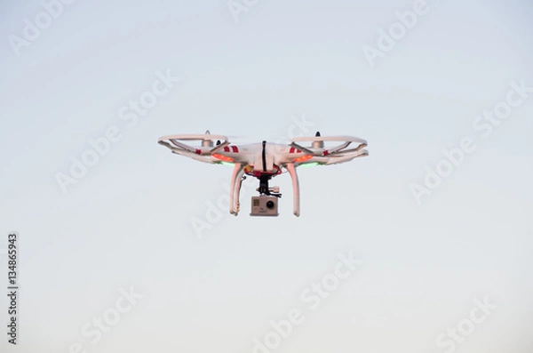 Fototapeta Flying drone with camera on the sky at sunset