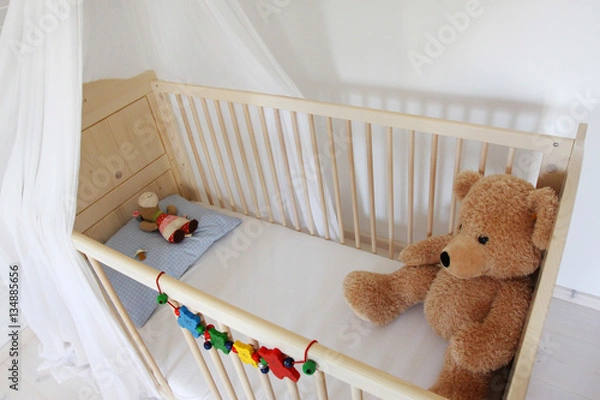 Obraz Ein Teddybär sitzt in einem Kinderbett