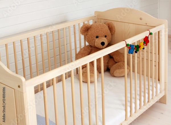 Obraz Ein Teddybär sitzt in einem Kinderbett