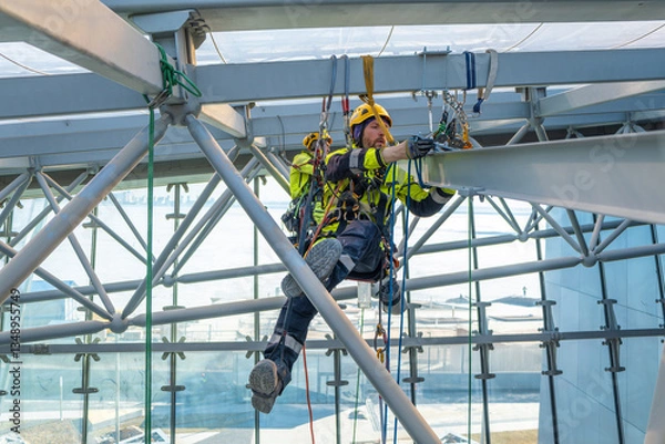 Fototapeta Rope access crew installs metal structure
