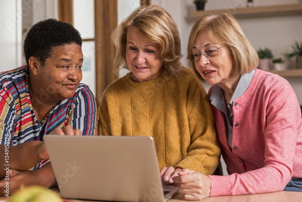 Obraz Senior Women Friends Gathering at Home. Three cheerful retired women enjoying friendly together in living room and chatting. Mature women use laptop computer typing on keyboard and pointing at screen
