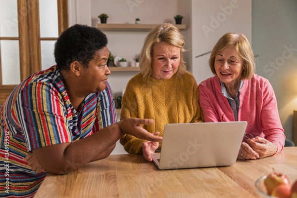Obraz Senior Women Friends Gathering at Home. Three cheerful retired women enjoying friendly together in living room and chatting. Mature women use laptop computer typing on keyboard and pointing at screen