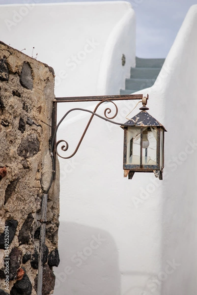 Fototapeta Vertical photo of a broken Greek traditional old lantern with black metal ornaments in Pyrgos Kallistis, Santorini, Greece. A perfect day trip from Fira to explore the islands mainland hidden gem