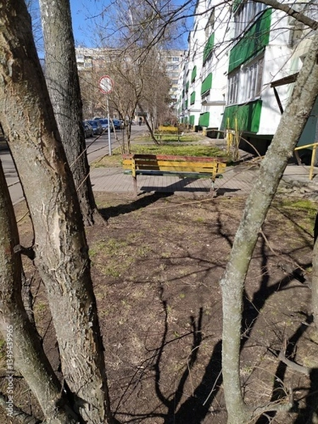 Obraz Bright benches on the adjacent territory of multi-storey buildings in early spring