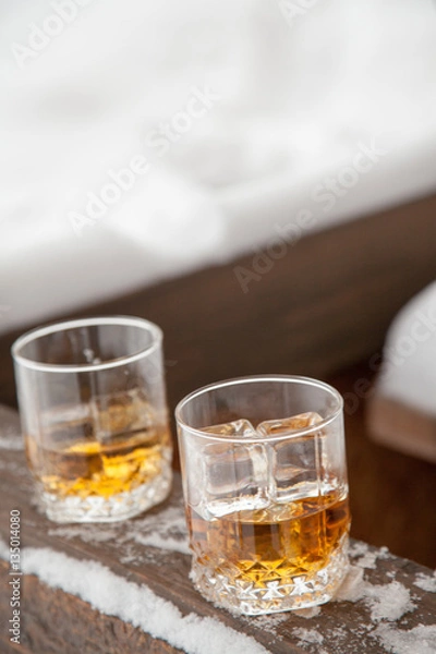 Fototapeta Two whiskey glasses in the snow on a winter background.