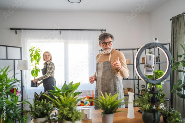 Obraz mature couple use cellphone for live streaming and presenting home plants