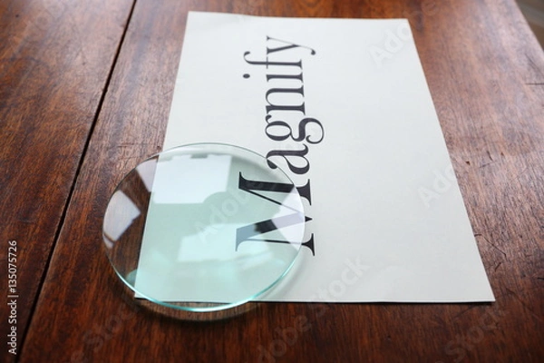 Fototapeta Magnify graphic text with glass lens on white paper