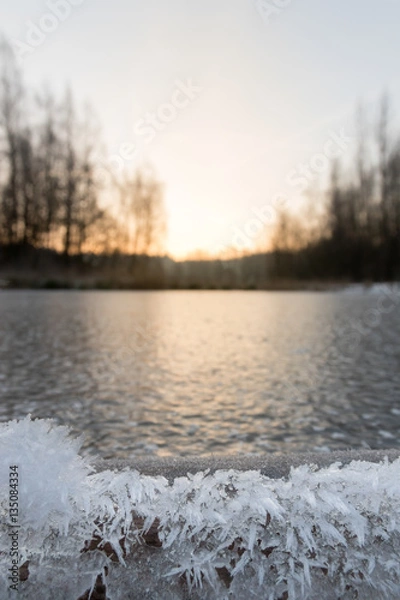 Fototapeta Low viewpoint on ice.
In the background a rising sun.
In the foreground artwork of ice crystals.