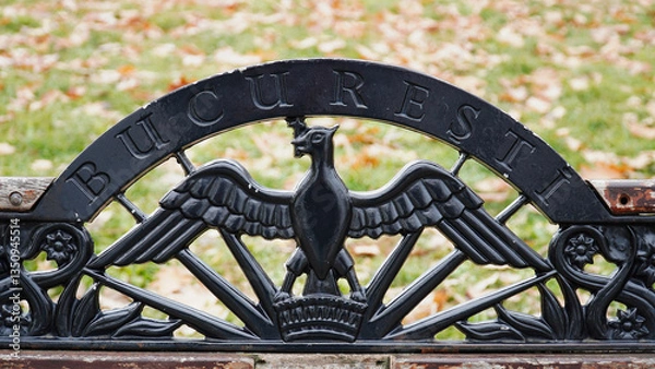 Fototapeta Ornate bench featuring Bucarest inscription and eagle design set in a lush park during autumn