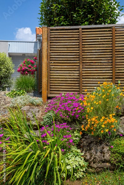 Fototapeta Charmant petit jardin paysagé avec ses fleurs et ses plantes vertes au printemps.