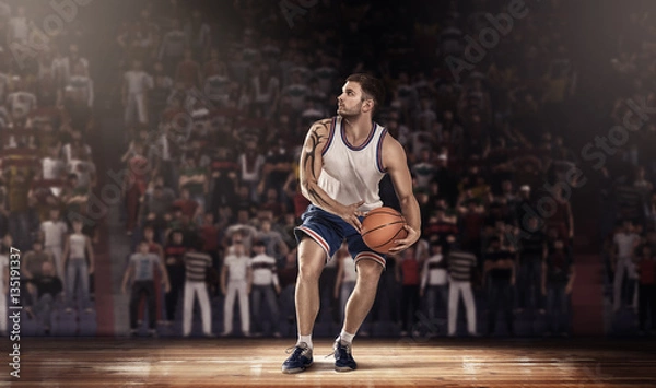 Fototapeta basketball player on parquet with ball in light rays