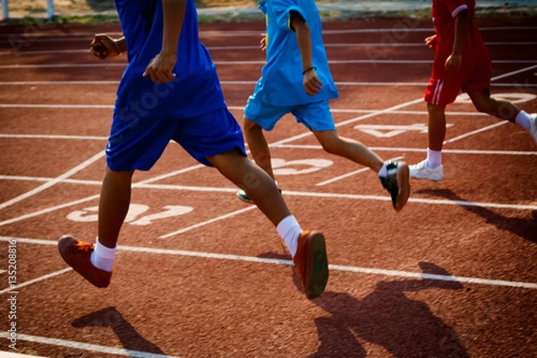 Fototapeta Group of boys running on running track in the stadium