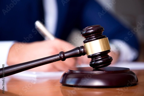 Fototapeta Handsome judge with gavel sitting in courtroom