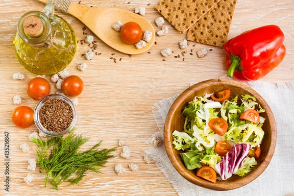 Fototapeta Натюрморт с овощами, зеленью, оливковым маслом и отрубями на деревянном столе. Вид сверху