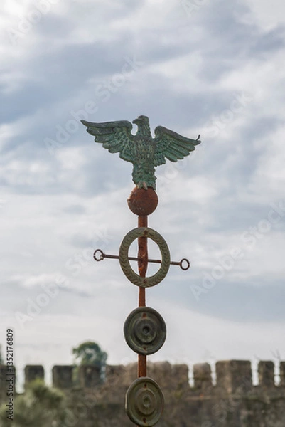 Fototapeta An ancient Roman eagle, covered with rust and patina, against a cloudy sky
