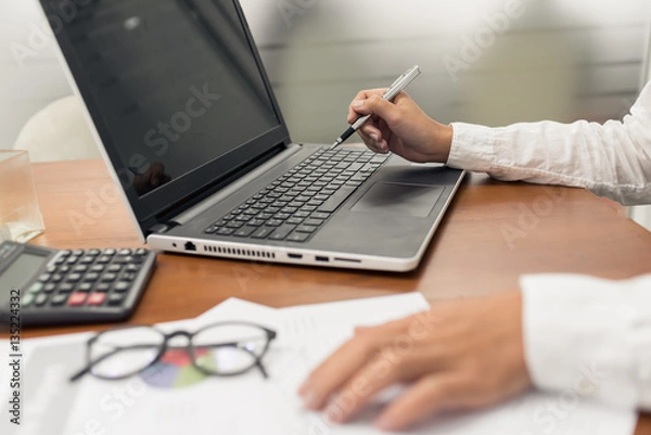 Fototapeta Young businesswoman working with document and laptop computer in office.