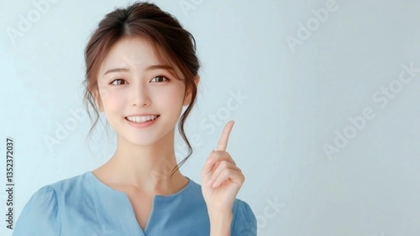 Obraz 笑顔で上を指差す若い女性。注目、案内、視線誘導に最適な人物素材。