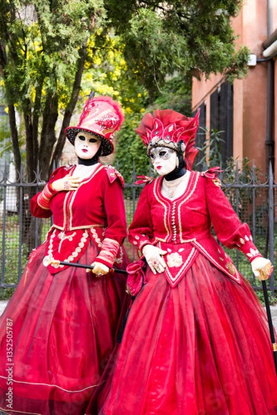 Fototapeta Venice, Italy - People dressed in carnival masks are photographed by tourists in the scenery of the ancient Venetian palaces