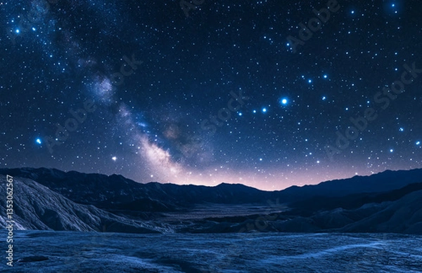Fototapeta A celestial landscape featuring a starry night sky over a mountainous terrain with a milky way view