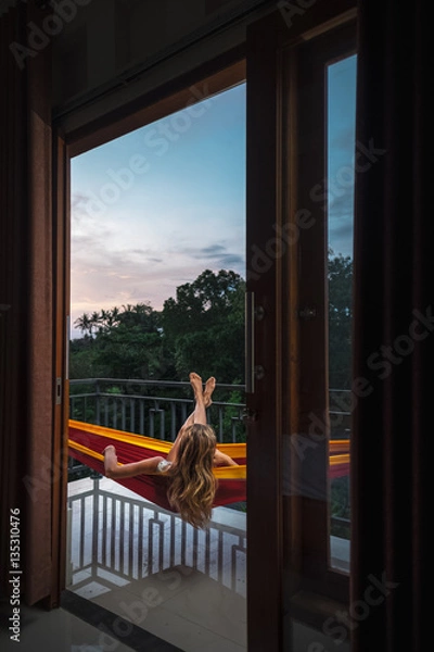 Fototapeta Woman relaxing in a hammock on the balcony