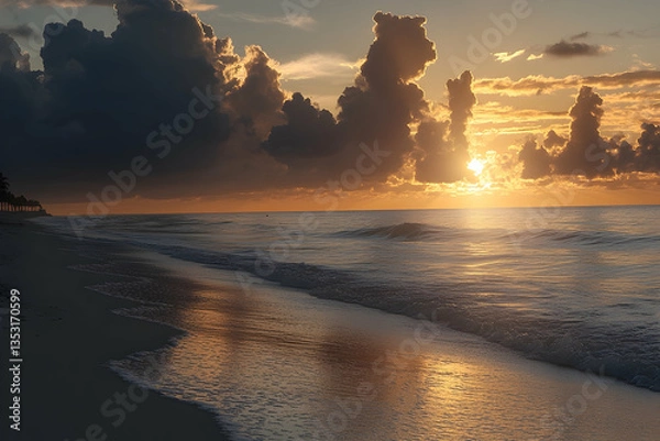 Fototapeta Sunrise over tranquil ocean beach, golden light reflects on wet sand
