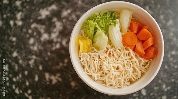 Obraz Close-up of a bowl of instant noodles with seasoning packets and fresh vegetables."