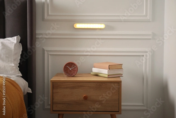 Obraz Glowing modern LED lamp on white wall in near bed indoors