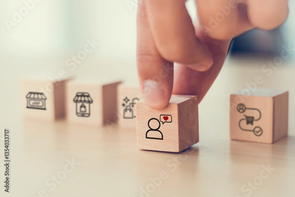 Fototapeta Seamless customer experience concept.  A close-up image of a hand selecting a wooden block with a customer icon and heart symbol, representing customer satisfaction, customer experience and engagement