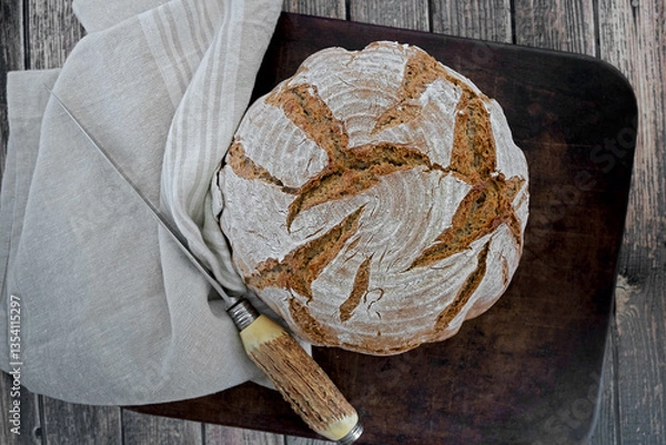 Obraz Homemade loaf of bread on a cloth and rustic stag horn knife