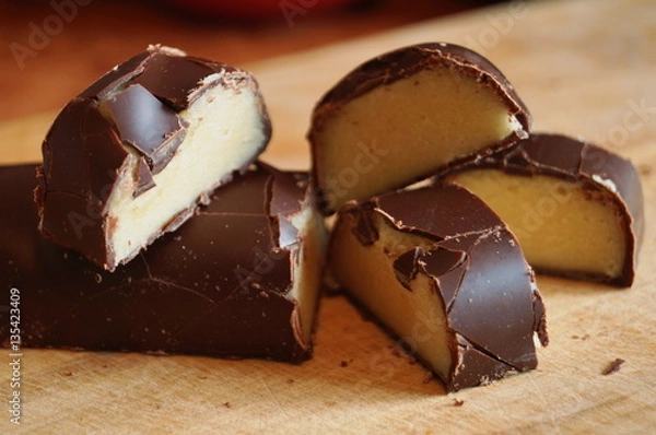 Fototapeta Candy with a marzipan covered with chocolate on a wooden table