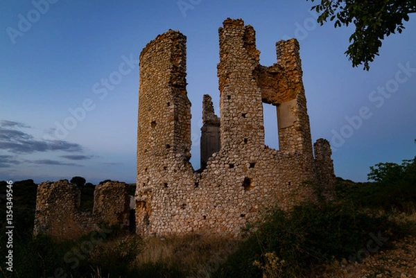 Fototapeta Ruins of an ancient stone structure at dusk surrounded by natural greenery