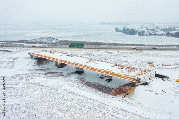 Fototapeta Construction of a bridge over the newly developed Highway D35, captured from above with a snowy construction site.