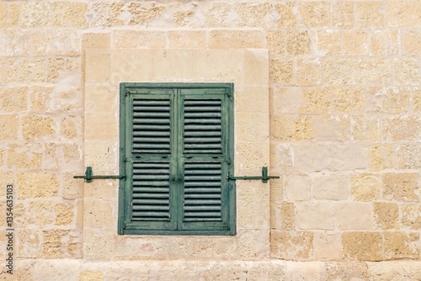 Obraz Traditional Maltese wooden window with green shutters in Valletta. A historic green shuttered window set in a limestone wall, reflecting Malta’s rich architectural heritage and Mediterranean character