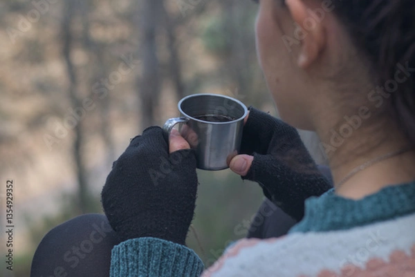 Obraz Hand with gloves holding thermal steel mug with coffee in the forest, copy space for text