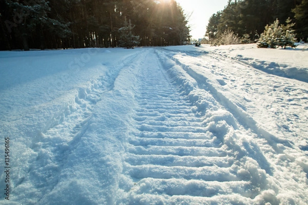 Fototapeta traces of a snowmobile on snow sun